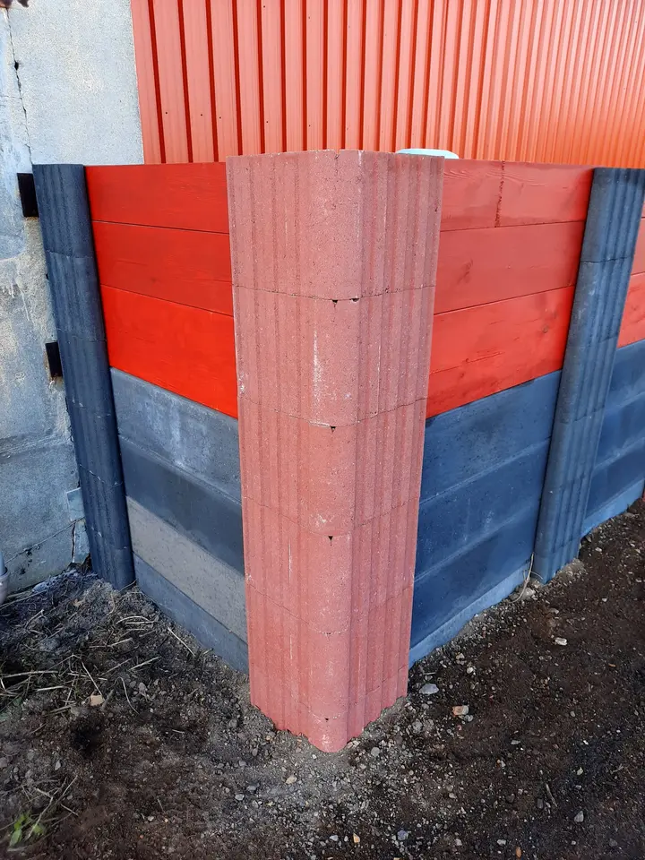 Ecke einer Sichtschutzwand mit rotem Vablo Eckpfosten, unten anthrazitfarbene Betonriegel, oben rot gestrichene Holzbohlen