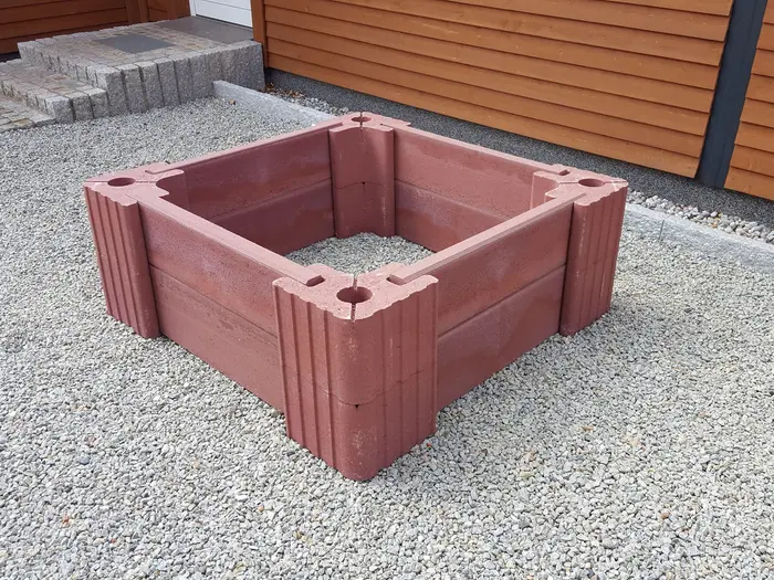 Quadratisches Hochbeet aus roten Vablo Ecksteinen und Betonriegeln in zwei Lagen, schräg von vorn auf Kies