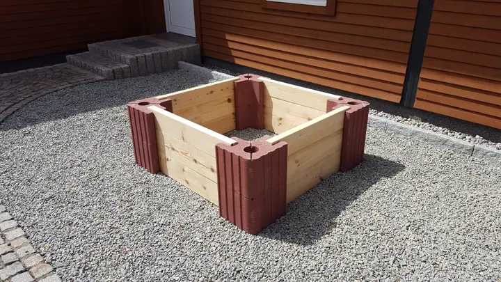 Quadratisches Hochbeet aus roten Vablo Ecksteinen und hellen Holzriegeln in zwei Lagen, schräg von vorn