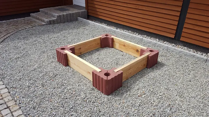 Niedrige quadratische Beeteinfassung aus roten Vablo Ecksteinen und hellen Holzriegeln, schräg von oben