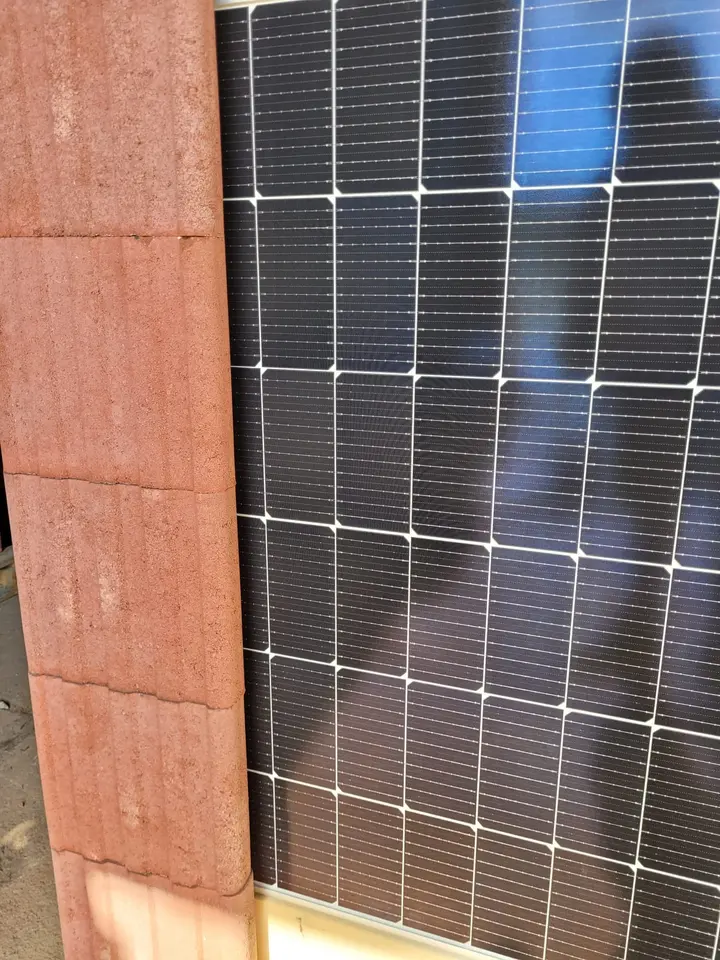 Nahansicht: roter Vablo Pfosten aus gestapelten Steinen, in dessen Nut der Rahmen eines Solarmoduls steckt