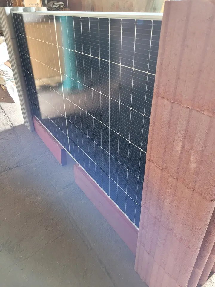 Seitlicher Blick an einem roten Vablo Pfosten entlang auf ein eingestecktes Solarmodul und eine rote Holzbohle am Boden